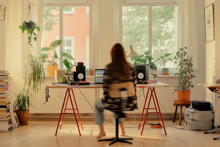 音楽制作者がスタジオで机に座り、Noteで始めた制作のアイデアを、Liveで発展させている。