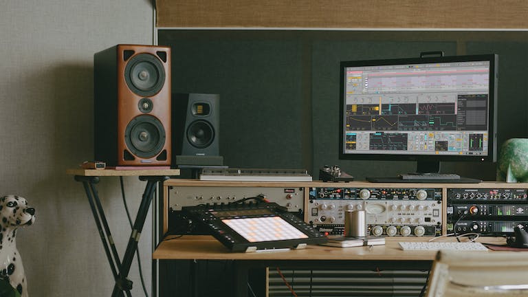A creative space complete with Push, speakers and a monitor displaying one of Live’s new Stacked Detail Views.
